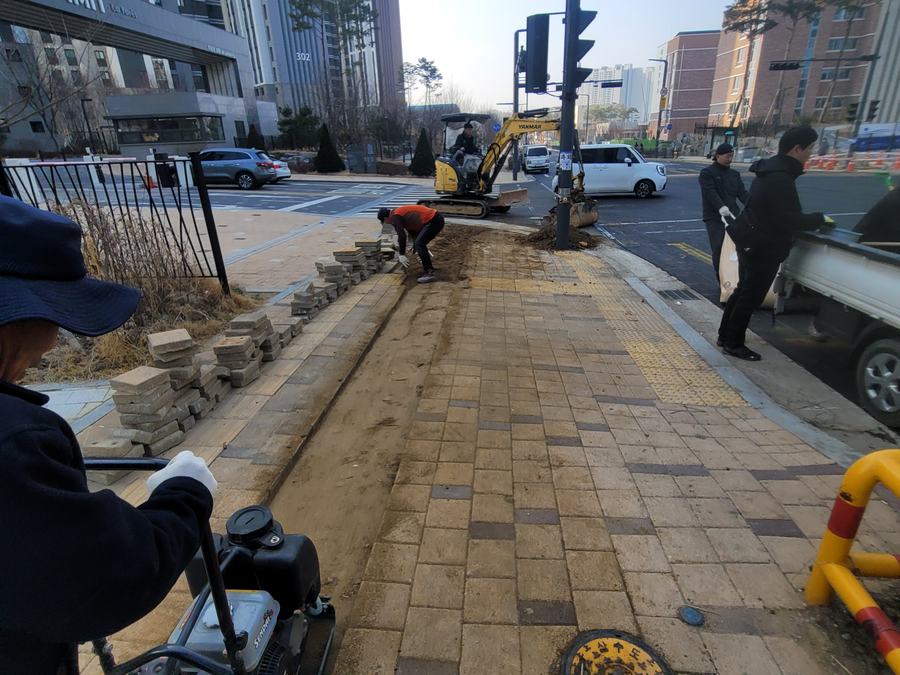 굴착기와 다짐기, 쌓아둔 블록 자재가 있는 보도블럭 시공 현장