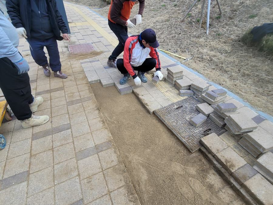 지그재그형 인터로킹 블록이 옆면 요철로 맞물려 배열된 보행로 시공 구간